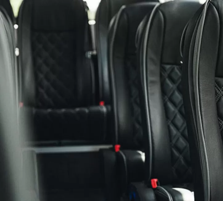 Luxury coach seats with black leather upholstery and diamond stitching.